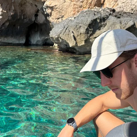 Charlie by the water, wearing a cap and sunglasses